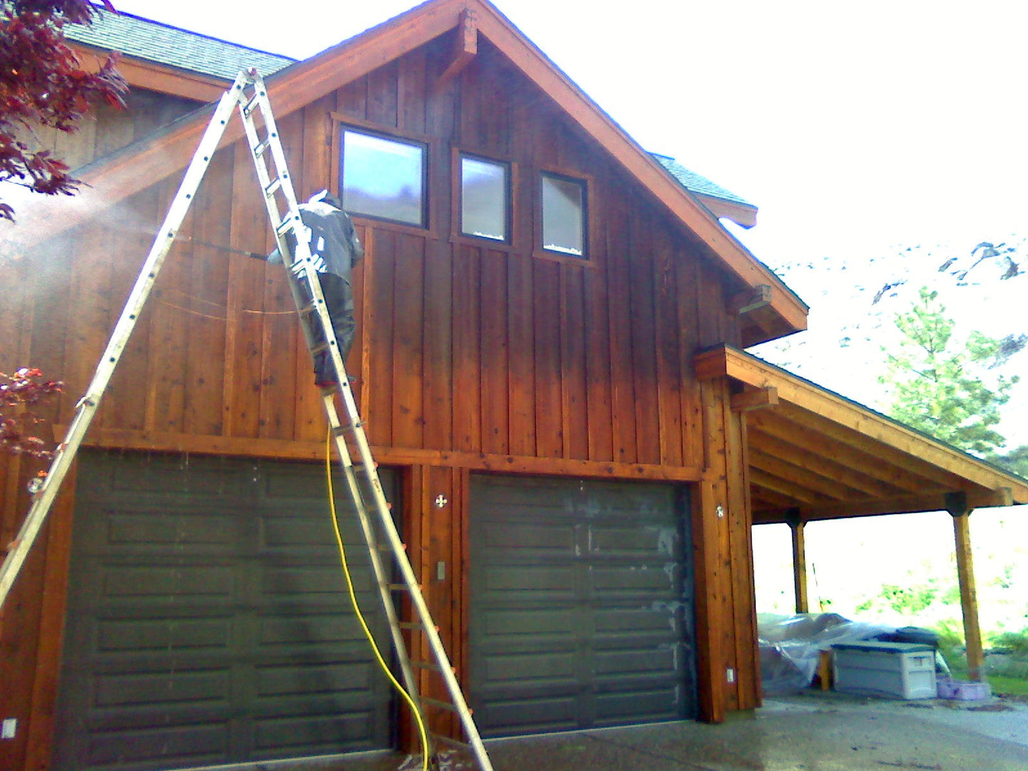 man on ladder powerwashing cedar siding using Lovitt's Wood Cleaner & Brightener